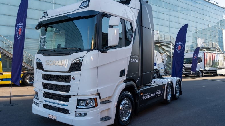 White Scania heavy-duty truck parked outside modern exhibition venue